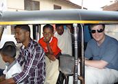 James in an auto rickshaw with the driver and his family